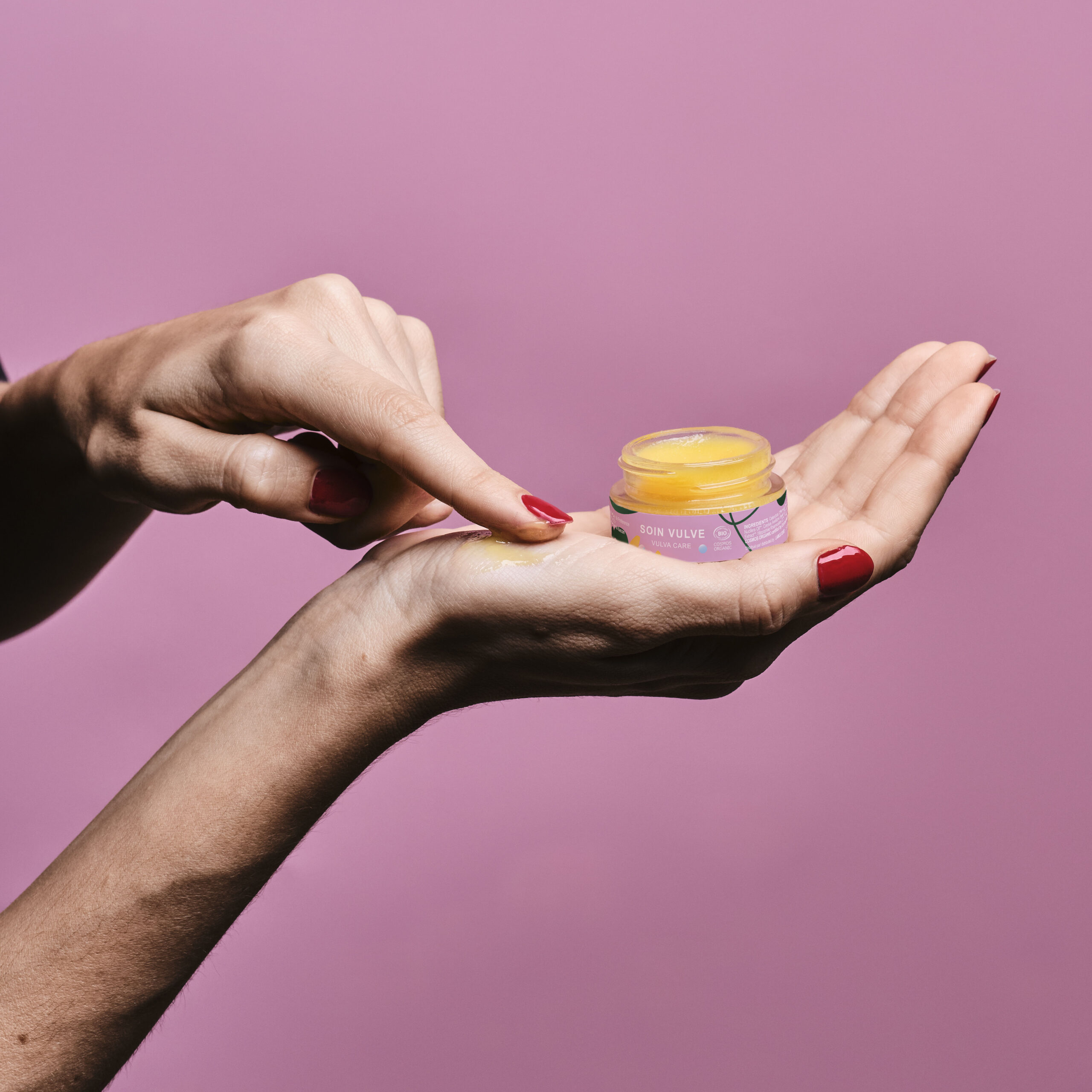 Mains de femme en train de tenir le baume Goliate et d'en appliquer sur sa main.