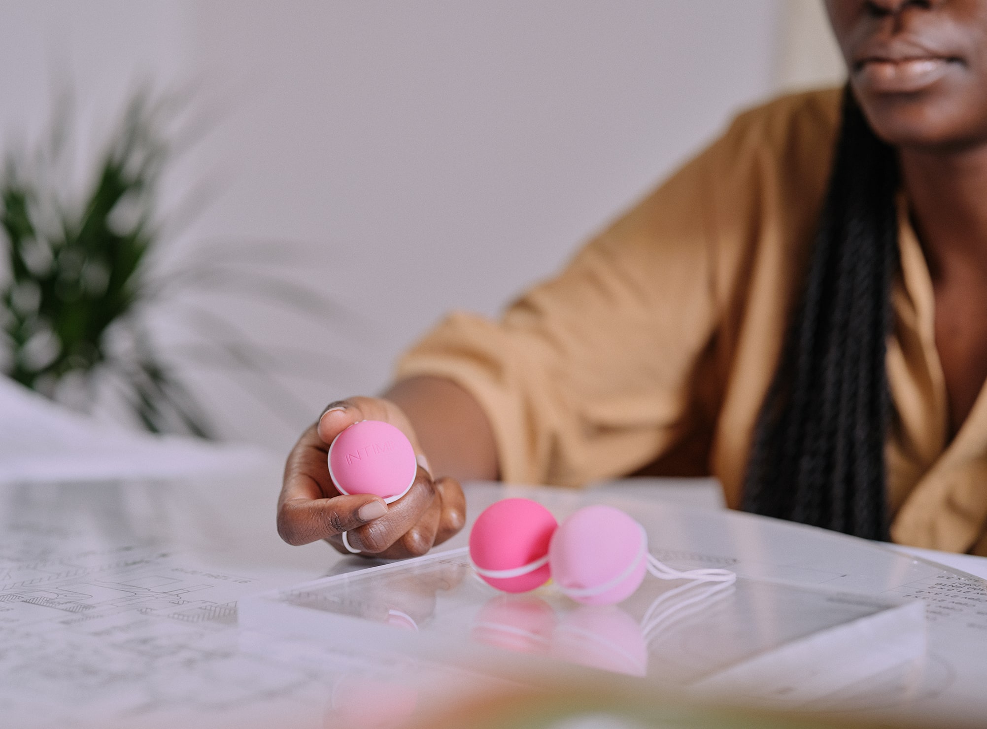 Les trois boules de Kegel présentées avec une femme qui en tient une en main, avec leurs différents grammages : 28 grammes, 38 grammes et 48 grammes.