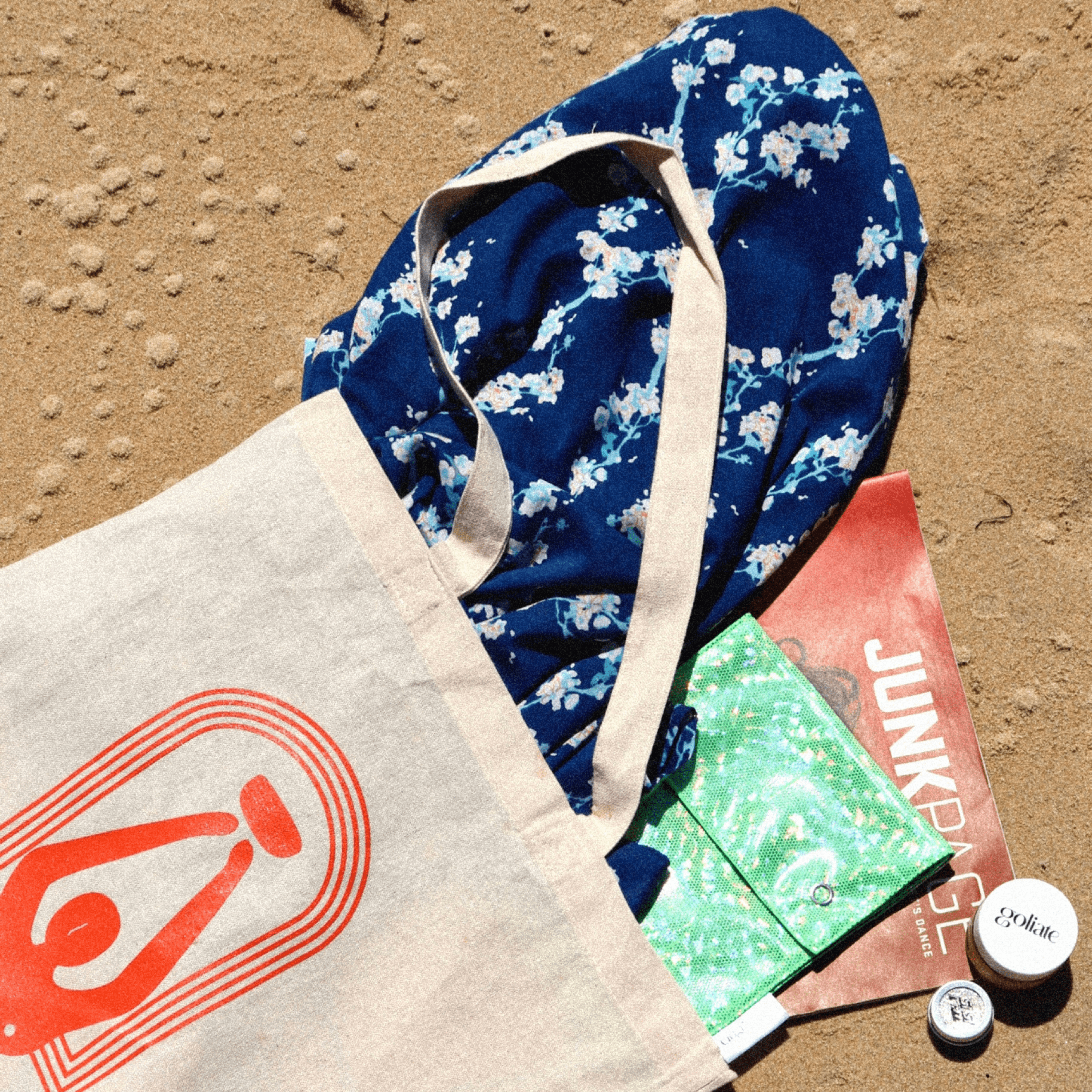 Tote bag jaya, baume vulve goliate, pochette goguette, kimono perdième et paillettes sisi la paillette présentés sur du sable